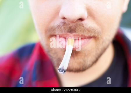 Alles hat ein Tor. Ein Mann, der Marihuana in einer Zigarette raucht. Stockfoto