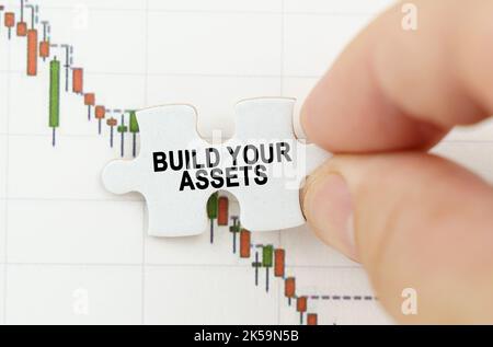 Geschäftskonzept. Vor dem Hintergrund der Zitatstabelle, ein Puzzle mit der Inschrift - bauen Sie Ihre Vermögenswerte Stockfoto