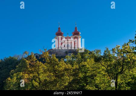 Banska Stiavnica, Slowakei - 28. September 2022: Blick auf den roten Kalvarienberg Banska Stiavnica unter einem blauen Himmel mit Wald im Vordergrund Stockfoto