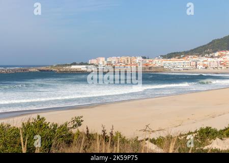 Breiter leerer Strand mit wunderschönen Wellen und weißer Stadt im Hintergrund. Vila Praia de Ancora, Portugal, Wahrzeichen. Küstenstadt. Stockfoto