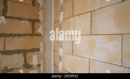 Befestigung von Metallstreifen an der Wand. Vorbereitung von Wänden zum Verputzen. Vorbereitung von Wänden zum Verputzen von Hauswänden mit Metallhaltern im Inneren. Stockfoto