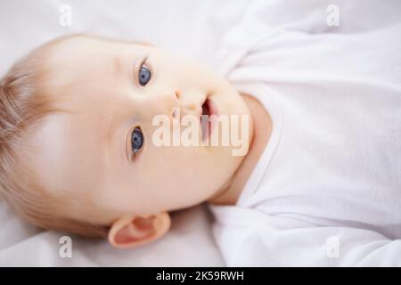 Nur in meiner Krippe zu chillen. Nahaufnahme eines entzückenden Babys, das sich hinlegt und lächelt. Stockfoto