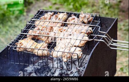 Leckere Chicken Wings Kochen auf Grill, im Freien. Gebratenes Hähnchenfleisch, Nahaufnahme Stockfoto