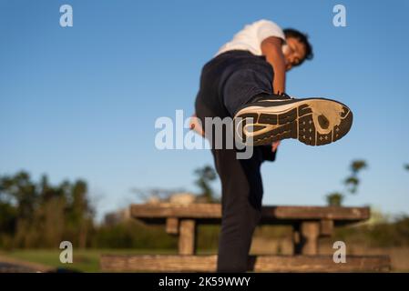 Ein Mann, der Laufschuhe mit abgenutzter Außensohle trägt, tritt in die Luft Stockfoto