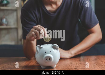 Investment Crypto Bitcoin Blockchain Finance Banking Wirtschaft Börse Handel Börse und Geld sparen Mann hält Münze Putting Sparschwein Geschäft Stockfoto