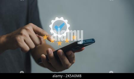 Das handhaltende Smartphone zeigt das Zeichen Service Qualitätssicherung 5 Stern, Garantie, Normen, ISO-Zertifizierung und Normungskonzept. Stockfoto