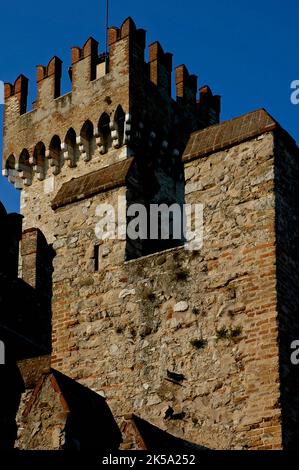 Schloss Castello Scaligero oder Rocca Scaligera in Sirmione, Lombardei, Italien. Es verfügt über Schwalbenschwanzzinnen, die für mittelalterliche Bogenschützen und Machicolationen entworfen wurden, oder „Mordlöcher“, um heißes Öl oder Felsbrocken auf Angreifer zu werfen. Die Burg wurde in den 1300er Jahren erbaut und hat ihren Namen von der Familie Della Scala, der Herrscherdynastie in Verona, die das Gebiet zu dieser Zeit dominierte und deren Mitglieder als Scaligeri oder Scaligers bekannt sind. Es ist eine der am besten erhaltenen Scaliger-Festungen. Stockfoto