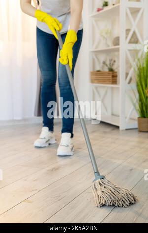 Reinigungsfirma. Hausmeisterin. Hausarbeit. Zimmerhygiene. Nicht erkennbare Frau in Schutzhandschuhen waschen laminierten Boden mit Mopp l wischen Stockfoto