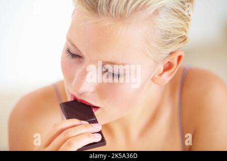 Genießen Sie den süßen Geschmack. Junge Frau genießt ein köstliches Stück Schokolade. Stockfoto