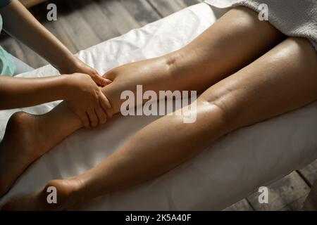 Massage der Beine im Spa, Nahaufnahme. Masseur, der mit dem Patienten arbeitet und seine Waden massiert. Stockfoto