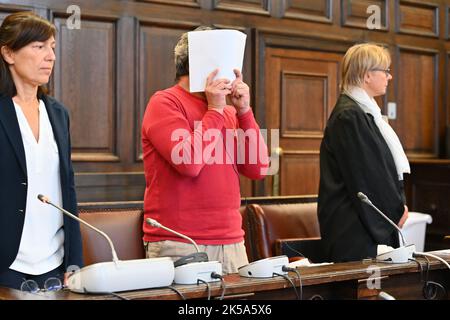 Hamburg, Deutschland. 07. Oktober 2022. Der Angeklagte (M) steht vor Beginn des Prozesses zwischen seinem Dolmetscher (l) und seinem Verteidiger (r) in einem Gerichtssaal im Strafjustizgebäude. Der 47-jährige Angeklagte soll einen 63-jährigen Mann mit einem Messer am Hamburger Michel (St. Michaels Hauptkirche) am Morgen des 28. März 2022. Quelle: Jonas Walzberg/dpa/Alamy Live News Stockfoto