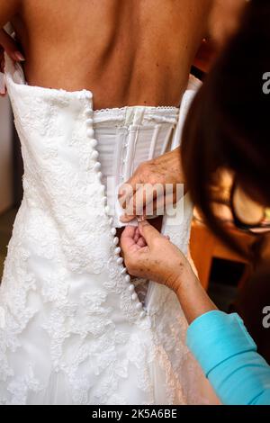 Nahaufnahme einer Mutter Knopf auf das weiße Hochzeitskleid ihrer Tochter Stockfoto