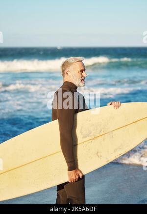 Senior man, Surfer am Strand und Surfbrett, bereit, im Urlaub oder im Urlaub in Australien zu surfen. Gesundheit, Fitness und ältere pensionierte männliche Ruhe nach Stockfoto