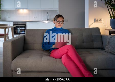 Junge Geschäftsfrau in Brille und blauem Pullover bereitet sich auf wichtige Treffen zu Hause vor Stockfoto