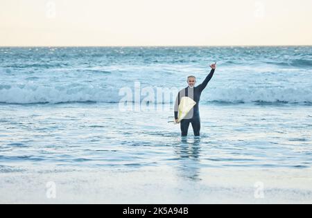 Shaka, Surfen und Sport mit einem reifen Mann, der im Sommer eine Handbewegung im Strandwasser macht. Surfer, Meer und Natur mit einem männlichen Athleten in der Stockfoto