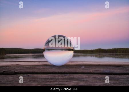 Glasball auf einem hölzernen Pier an einem schwedischen See zur Abendstunde. Natur aus Skandinavien Stockfoto