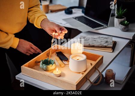 Meditation, Entspannung nach der Arbeit. Frau macht sich bereit, meditiert und zündet indischen Räucherstäbchen und Kerzen an. Frau Hände mit Rauch indian Stockfoto
