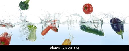 Mischen Sie verschiedene Gemüse spritzt in Wasser. Seitenpanorama auf weißem Hintergrund. Stockfoto