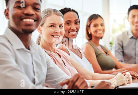 Geschäftsteam, Publikum und Vielfalt mit zufriedenen Mitarbeitern, die für ein Zusammenarbeitstreffen, eine Schulung oder einen Workshop am Tisch sitzen. Portrait von Männern und Stockfoto