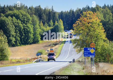 Das Pilotfahrzeug warnt den Verkehr vor übergroßer Last. Gelber Volvo FH16 Sattelanhänger zieht LNG-Speicher auf der Autobahn 110. Salo, Finnland. September 22, 2022 Stockfoto