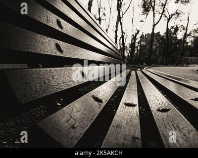 Nahaufnahme einer leeren Holzbank im Freien in einem Park. Stockfoto