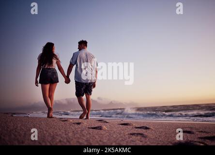 Paar, Hände haltend und Liebe zum Strand Gehen Sie gemeinsam in romantischen Sommeruntergang im Freien. Hand halten von Mann und Frau auf einem schönen zu Fuß Stockfoto