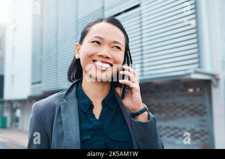 Asiatische Frau, Telefonanruf und Gespräch mit Geschäftskontakt in mit einem Lächeln auf der Straße der Stadt, während Networking auf dem Smartphone. Fröhliche Angestellte in der Firma Stockfoto