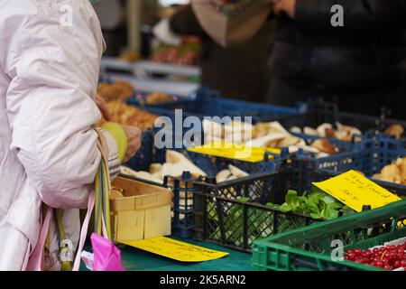 Eine alte Frau, die Steinpilze und Pfifferlinge auf dem Bauernmarkt in Wiesbaden kauft Stockfoto