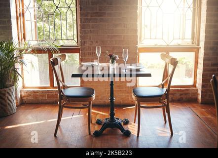 Leeres Zimmer, Gläser und Tisch in einem Restaurant für ein romantisches Date, eine Feier oder ein luxuriöses Abendessen. Weinglas für Champagner, Wein oder Alkoholgetränk Stockfoto