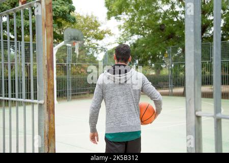 Rückansicht eines Basketballspielers, der auf einen öffentlichen Platz im Freien eintritt Stockfoto