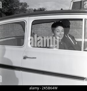 1964, historisch, Blick durch ein Autofenster der berühmten englischen Ballerina Margot Fonteyn, die vielleicht einen Ford Anglia fährt. Es ist wahrscheinlich, dass das Bild in der Nähe des Stoke Mandeville Hospital in Buckinghamshire, England, aufgenommen wurde, wo ihr Mann, Roberto Arias, Ein pananischer Politiker, der bei einem Attentat schwer verletzt worden war, wurde in seinem Nationalen Zentrum für Wirbelsäulenverletzungen behandelt. Im Jahr 60s ging Fontyen eine historische Tanzpartnerschaft mit dem russischen klassischen Tänzer Rudolf Nureyev ein. Stockfoto