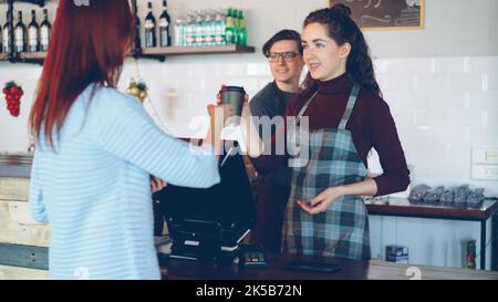 Junge Kundin kauft Kaffee zum Mitnehmen in einem modernen Café. Stockfoto