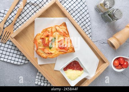 Pizzabrot mit Garnelen, Krabbenstäbchen, Tomaten, Käse in einem Holztablett mit Sauce von oben Stockfoto