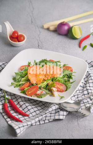 Würziger Lachssalat auf Teller mit Tomaten und Chili Stockfoto