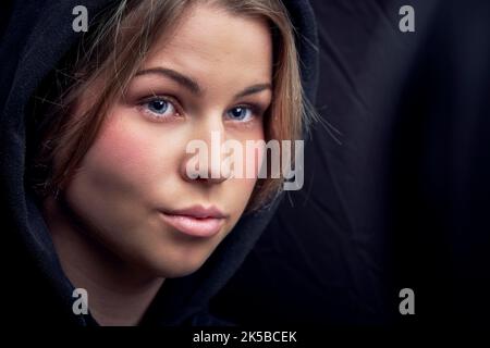Nahaufnahme einer jungen Frau mit schwarzer Kapuze Stockfoto