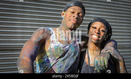 Zwei Nachtschwärmer haben Spaß, bedeckt mit farbigem Pulver, und malen, bei der frühmorgendlichen J'ouvert-Feier, Notting Hill Carnival, London Stockfoto