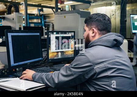 Perm, Russland - 21. September 2022: Der Bediener steuert die Industriemaschine, während er vor den Monitoren sitzt Stockfoto