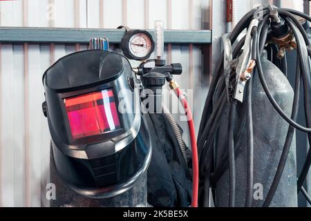 Ausrüstung für das Gasschweißen in der Werkstatt: Maske, Zylinder mit Manometer, Schläuche Stockfoto