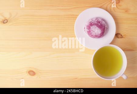 Japanischer Purple Sweet Potato Daifuku oder Red Bean Paste Füllung Reiskuchen mit grünem Tee auf Holztisch Stockfoto