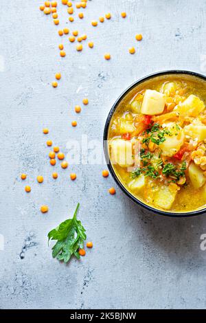 Suppe mit roten Linsen und Gemüse in einer Schüssel auf blauem Hintergrund.Traditionelles Gericht der türkischen oder arabischen Küche, vegane gesunde Lebensmittel. Stockfoto