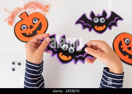 Kinderhände halten halloween Fledermaus Dekorationen mit gruseligen Gesicht Stockfoto