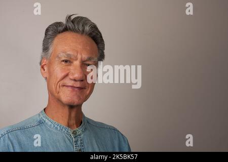 Heads Shot Portrait eines reifen Mannes 60 plus in einem hellblauen Denim-Hemd Stockfoto