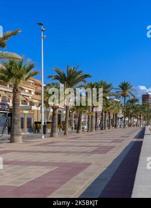 Die Küste von El Campello an der Costa Blanca in Spanien, in der Nähe von Alicante. Gesäumt von Geschäften und Cafés mit Schatten von den Palmen. Stockfoto