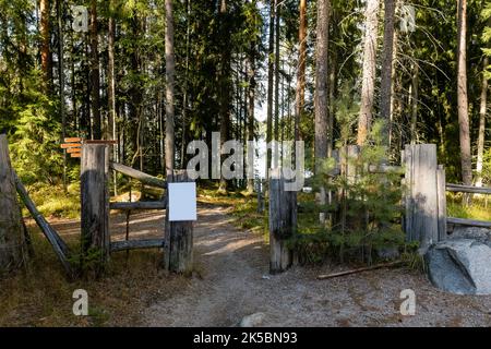 Leeres weißes Schild am Tor eines alten Holzzauns im Wald Stockfoto