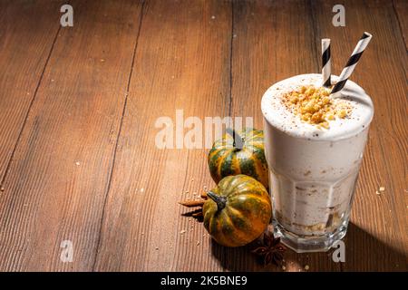 Hausgemachter, beladen Kürbis-Gewürz-Milchshake mit Eis und herber Krümel, in einem Glas mit kleinen Kürbissen-Dekor, Pekannüssen und Gewürzen, gesund f Stockfoto