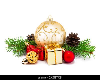 Weihnachtliche Äste und festliche Dekoration auf weißem Hintergrund. Weihnachtsdekoration goldene und rote Kugeln mit Tannenzapfen und Tannenzweigen iso Stockfoto