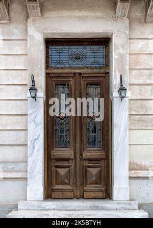 Alte Holztür im Zentrum von Athen in Griechenland. Große Tür mit Holzstruktur und zwei Leuchten. Stockfoto