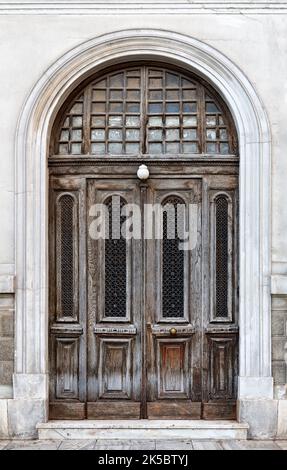 Alte Holztür im Zentrum von Athen in Griechenland. Große Tür mit Holzstruktur und abgerundeten Ecken. Stockfoto