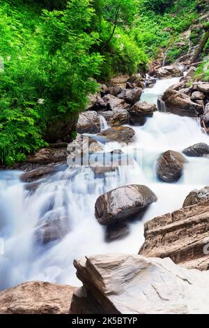 Wasserfall Kaskade auf Bergfelsen. Ein Bergwasserfall fließt über die Felsen. Blick auf den Wasserfall des tiefen Regenwaldes. Stockfoto