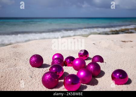 Rosa Weihnachtskugeln am Strand. Weihnachten in den Tropen. Selektiver Fokus Stockfoto